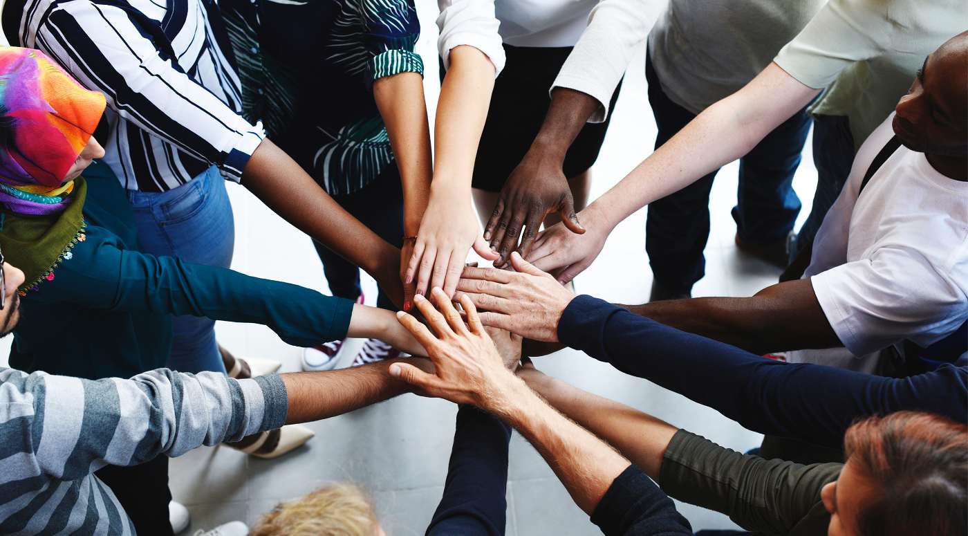 Mains de plusieurs personnes réunies au centre en signe de coopération
