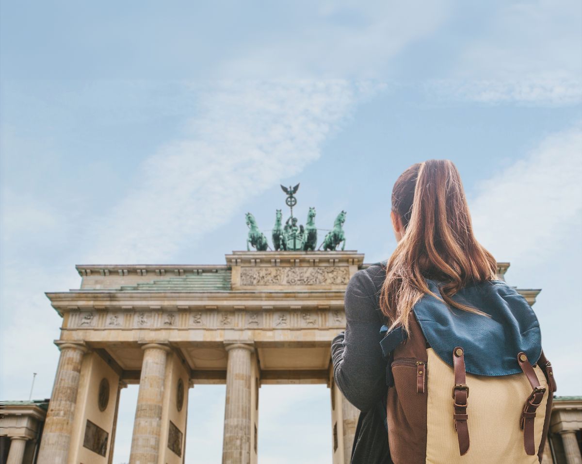 une femme avec un sac a dos devant le brandenburger Tor